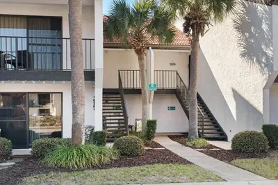 a building with palm trees and stairs in front of it at Edgewater Golf Villa 2110 in Panama City Beach