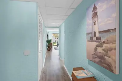 a hallway with blue walls and a painting of a lighthouse at Edgewater Golf Villa 2110 in Panama City Beach
