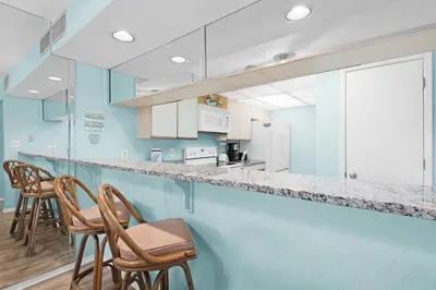 a blue kitchen with chairs and a counter at Edgewater Golf Villa 2110 in Panama City Beach