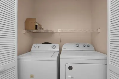 a laundry room with two washes and a box on a shelf at Edgewater Golf Villa 2110 in Panama City Beach