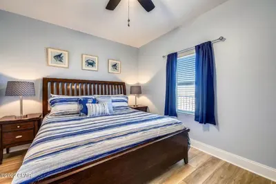 a bedroom with a bed and a window with blue curtains at Beautiful Condo with Ocean View from 15th Floor in Panama City Beach