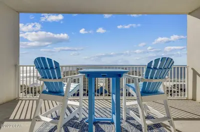 a pair of blue chairs and a table on a balcony at Beautiful Condo with Ocean View from 15th Floor in Panama City Beach