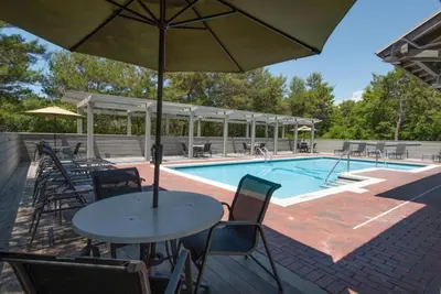 a table with an umbrella next to a swimming pool at Magnolia Cottages by the Sea by Panhandle Getaways in Seacrest