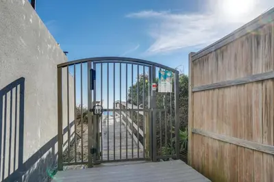 a gate to a driveway with a wooden fence at Magnolia Cottages by the Sea by Panhandle Getaways in Seacrest