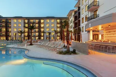 a hotel with a swimming pool in front of a building at Embassy Suites By Hilton Panama City Beach Resort in Panama City Beach