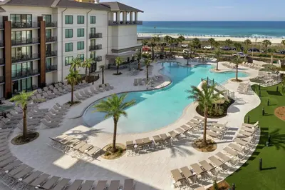 an aerial view of a resort with a pool and chairs at Embassy Suites By Hilton Panama City Beach Resort in Panama City Beach