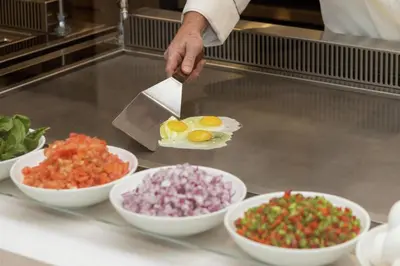 a chef is preparing vegetables in bowls on a counter at Embassy Suites By Hilton Panama City Beach Resort in Panama City Beach