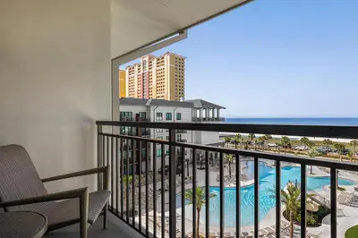 a balcony with a view of a pool and the ocean at Embassy Suites By Hilton Panama City Beach Resort in Panama City Beach