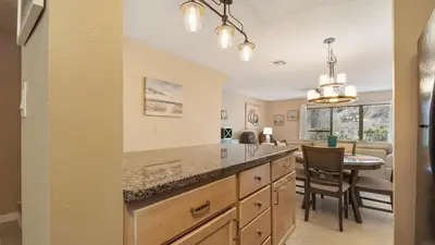 a kitchen with a table and a dining room at Beach Walk 10C by Sand Seeker Vacations in Panama City Beach