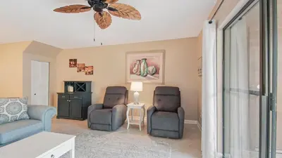 a living room with two chairs and a ceiling fan at Beach Walk 10C by Sand Seeker Vacations in Panama City Beach