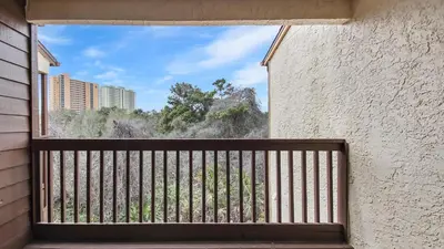 a balcony with a window with a view of trees at Beach Walk 10C by Sand Seeker Vacations in Panama City Beach