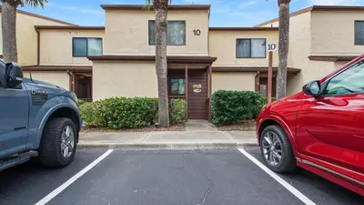 two cars parked in a parking lot in front of a building at Beach Walk 10C by Sand Seeker Vacations in Panama City Beach