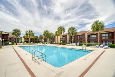 a swimming pool with palm trees and buildings at Beach Walk 10C by Sand Seeker Vacations in Panama City Beach