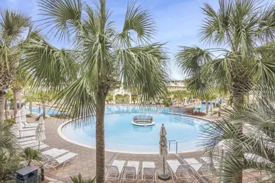 a large swimming pool with palm trees and chairs at Villas at Seacrest by Panhandle Getaways in Seacrest