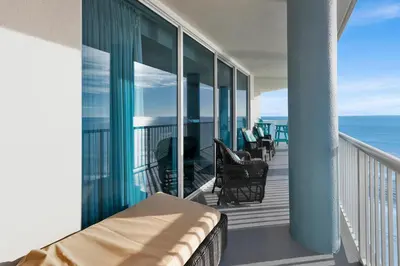 a balcony with a bed and chairs and the ocean at Palazzo 408 in Panama City Beach