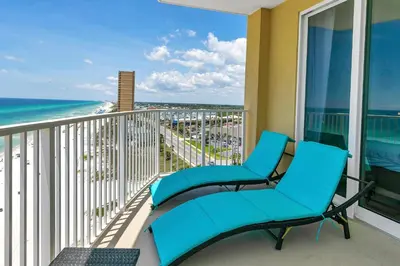 a balcony with two blue chairs and the ocean at Emerald Isle 1201 in Panama City Beach
