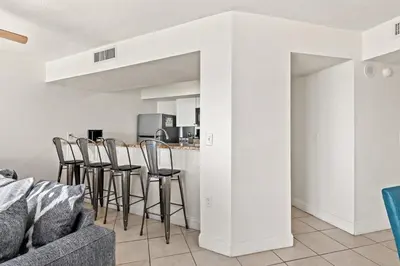 a living room with a couch and a bar with stools at Enjoy A Birds Eye View at Panama City Beach in Panama City Beach