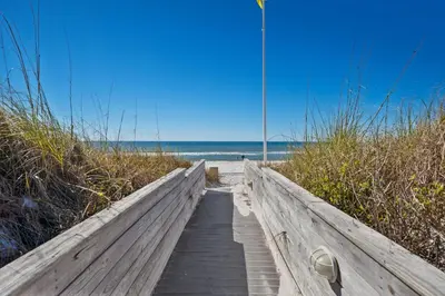 a wooden path to the beach with the ocean in the background at Enjoy A Birds Eye View at Panama City Beach in Panama City Beach