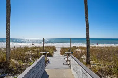 a boardwalk leading to a beach with chairs and the ocean at Enjoy A Birds Eye View at Panama City Beach in Panama City Beach