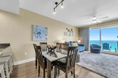 a dining room and living room with a view of the ocean at Sterling Breeze 1204 in Panama City Beach