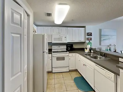 a kitchen with white cabinets and a white refrigerator at Majestic Beach Towers I #1004 in Panama City Beach
