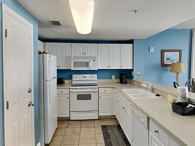 a kitchen with white appliances and blue walls at Majestic Beach Towers I #1015 in Panama City Beach