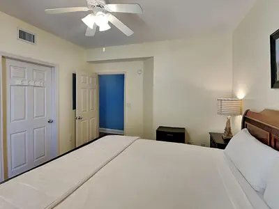 a bedroom with a white bed and a ceiling fan at Majestic Beach Towers I #1015 in Panama City Beach