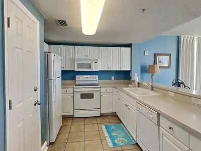 a kitchen with white appliances and blue walls at Majestic Beach Towers I #1015 in Panama City Beach