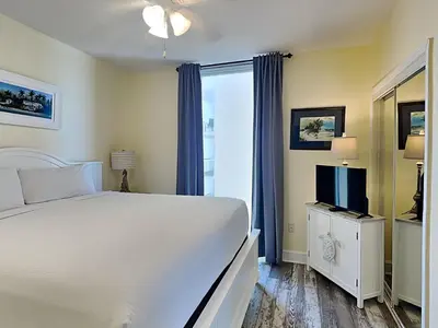 a bedroom with a white bed and a television at Majestic Beach Towers I #1015 in Panama City Beach