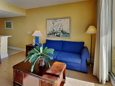 a living room with a blue couch and a table at Majestic Beach Towers I #1414 in Panama City Beach