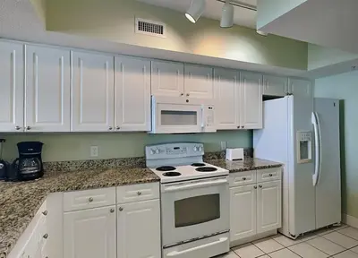 a kitchen with white cabinets and a stove and refrigerator at Emerald Beach #1531 in Panama City Beach