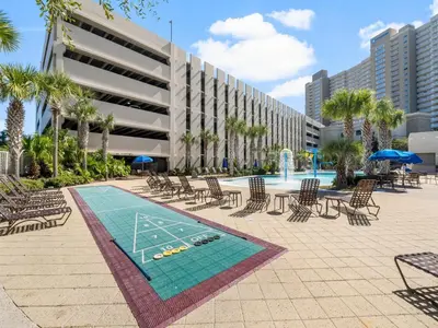 a pool with chairs and a table and a volleyball court at Emerald Beach #1531 in Panama City Beach