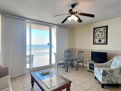 a living room with a table and a view of the ocean at Majestic Beach Towers I #913 in Panama City Beach