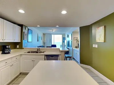 a kitchen with white cabinets and green walls at Majestic Beach Towers II #1006 in Panama City Beach