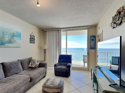 a living room with a couch and a chair and the ocean at Majestic Beach Towers II #1006 in Panama City Beach