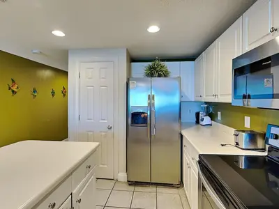 a kitchen with a stainless steel refrigerator and white cabinets at Majestic Beach Towers II #1006 in Panama City Beach