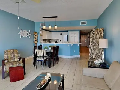 a living room and kitchen with blue walls and a table at Majestic Beach Towers II #707 in Panama City Beach