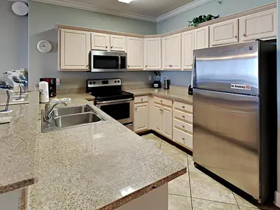 a kitchen with white cabinets and a stainless steel refrigerator at Twin Palms #1805A in Panama City Beach