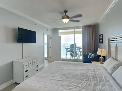 a bedroom with a bed and a television and a balcony at Majestic Beach Towers II #1902 in Panama City Beach