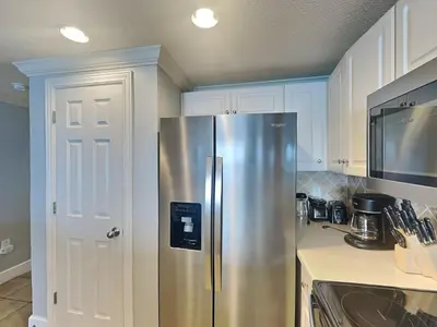 a stainless steel refrigerator in a kitchen with white cabinets at Majestic Beach Towers II #1902 in Panama City Beach