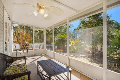 a screened porch with a ceiling fan and a table at The Sand Castle in Panama City Beach