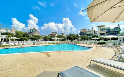 a swimming pool with an umbrella and some houses at GULF FRONT PENTHOUSE CONDO COMPLIMENTARY GOLF CART 407 Compass Point 1, WaterSound - 3 BR, SLPS 8 condo in Panama City Beach