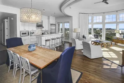 a kitchen and living room with a wooden table and chairs at GULF FRONT PENTHOUSE CONDO COMPLIMENTARY GOLF CART 407 Compass Point 1, WaterSound - 3 BR, SLPS 8 condo in Panama City Beach