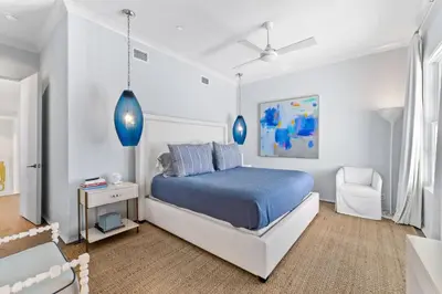 a white bedroom with a blue bed and a chair at Enchantment - Beach Front, Private Pool, Private Beach Access - 5BR 5BTH Home home in Panama City Beach