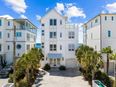 a large white apartment building with palm trees at Enchantment - Beach Front, Private Pool, Private Beach Access - 5BR 5BTH Home home in Panama City Beach