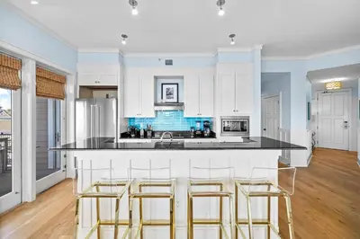 a kitchen with white cabinets and a counter with bar stools at GULF VIEWS from ALL Bedrooms! 308 Compass Point 1 in WaterSound - Short walk to the beach and pool condo in Panama City Beach