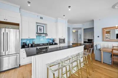a kitchen with white cabinets and a bar with stools at GULF VIEWS from ALL Bedrooms! 308 Compass Point 1 in WaterSound - Short walk to the beach and pool condo in Panama City Beach