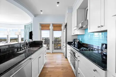 a kitchen with white cabinets and black counter tops at GULF VIEWS from ALL Bedrooms! 308 Compass Point 1 in WaterSound - Short walk to the beach and pool condo in Panama City Beach