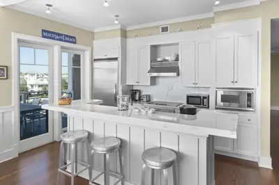 a kitchen with white cabinets and bar stools at NEW RENTAL Beach Front Condo in WaterSound Beach FL with Stunning Views! condo in Panama City Beach