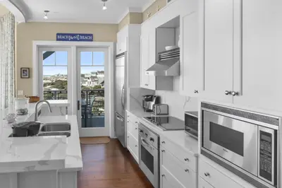 a white kitchen with a sink and a counter at NEW RENTAL Beach Front Condo in WaterSound Beach FL with Stunning Views! condo in Panama City Beach